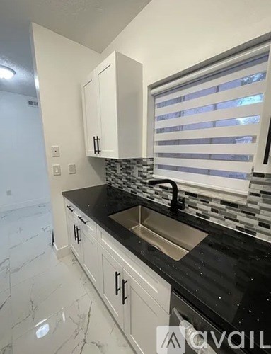A kitchen with white cabinets and a black countertop.