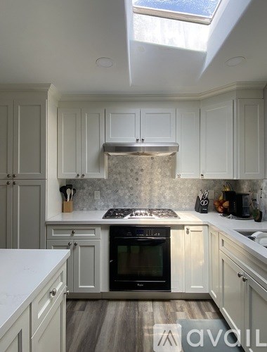A kitchen with white cabinets and a black stove top.