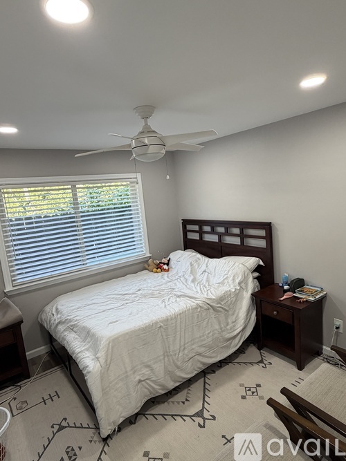 A bedroom with a bed, nightstand, and window with blinds.
