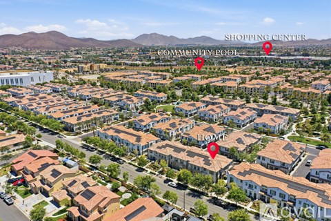 An aerial view of a neighborhood with a shopping center, community pool, and homes.