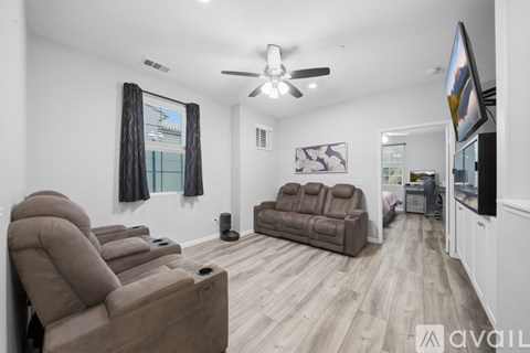 A living room with a brown couch and a fan on the ceiling.