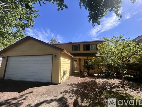 A house with a garage and a tree in front.