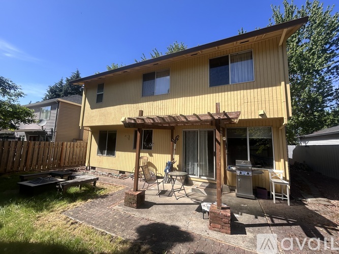 A yellow house with a patio and a grill.