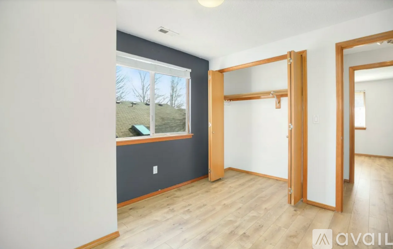 A room with a window and a view of a lawn and trees.