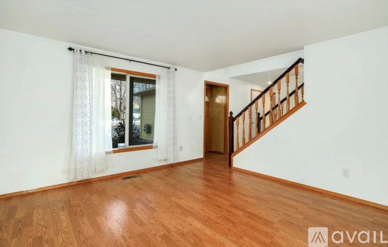 A room with wooden floors and a staircase leading to another room.
