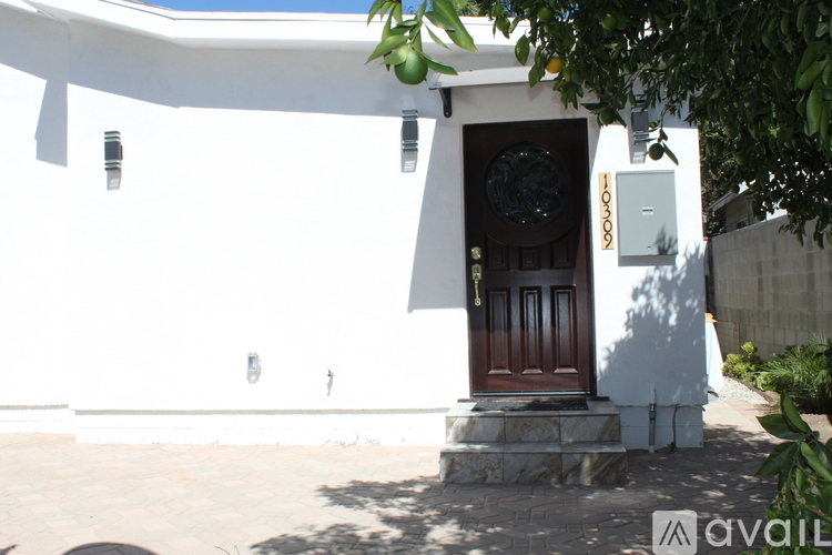 A white house with a brown door and a small window above it.