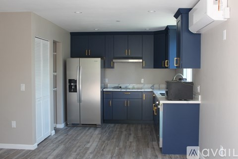 A kitchen with dark blue cabinets and a white refrigerator.