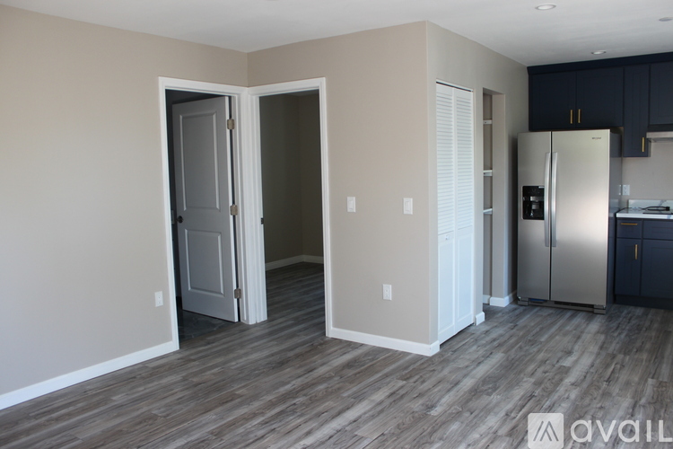 A kitchen area with a refrigerator, cabinets, and a doorway leading to another room.
