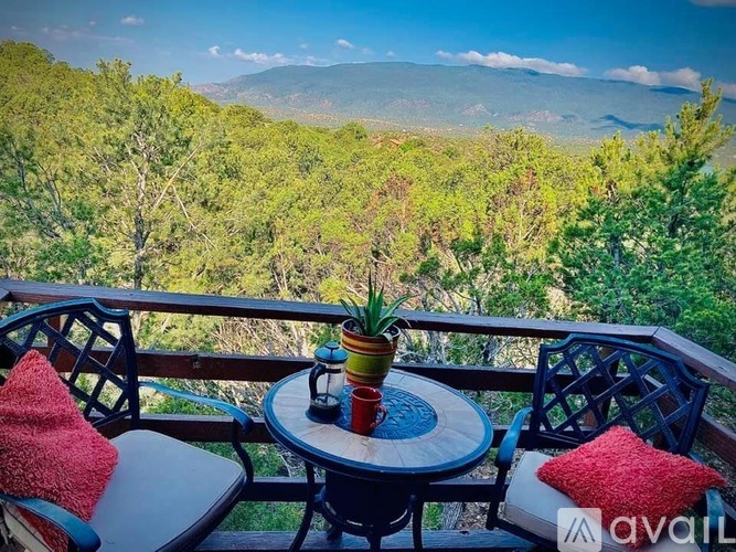 A balcony with a table and chairs overlooking a green landscape.