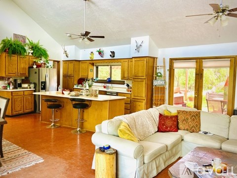 A living room with a white couch and a kitchen area in the background.