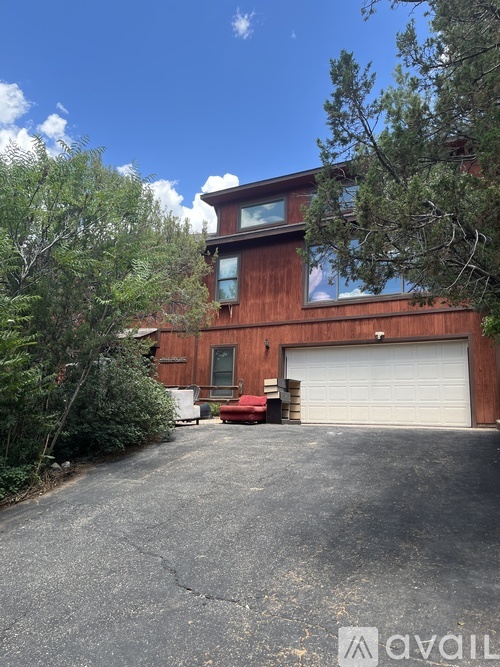 A house with a garage and a driveway surrounded by trees.
