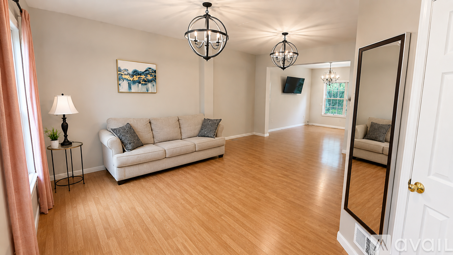 A living room with a white couch and a painting on the wall.