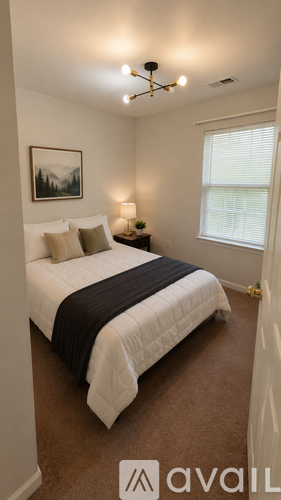 A bedroom with a bed, a lamp, and a painting on the wall.