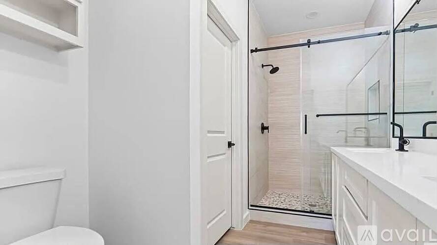 A white bathroom with a toilet, sink, and shower.