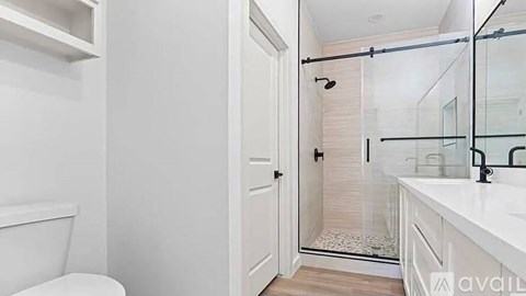 A white bathroom with a toilet, sink, and shower.