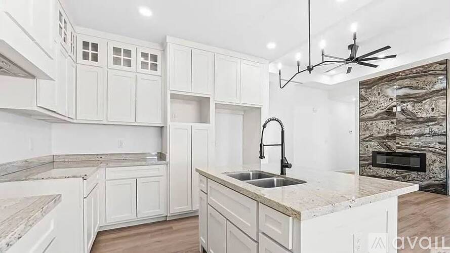 A modern kitchen with white cabinets and a marble countertop.