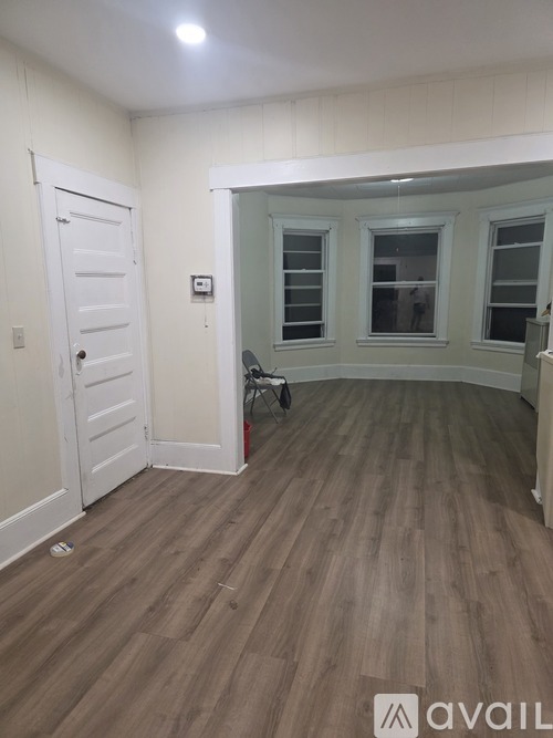 A room with a white door and a wooden floor.