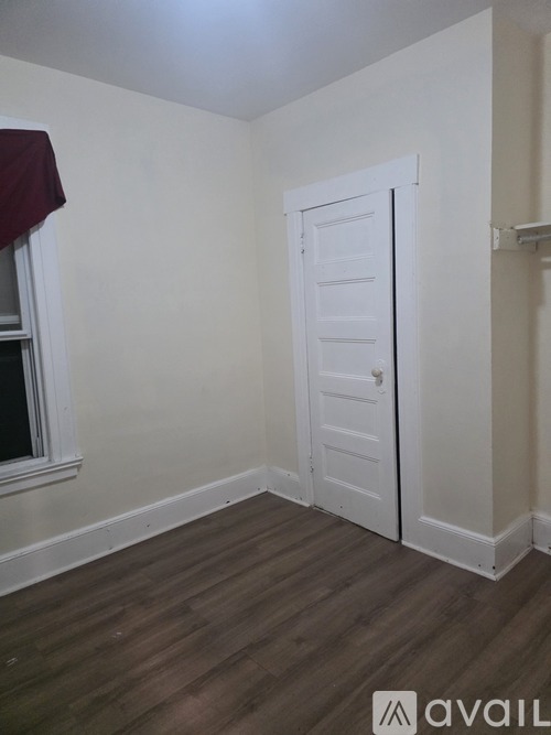A room with a white door and wooden flooring.