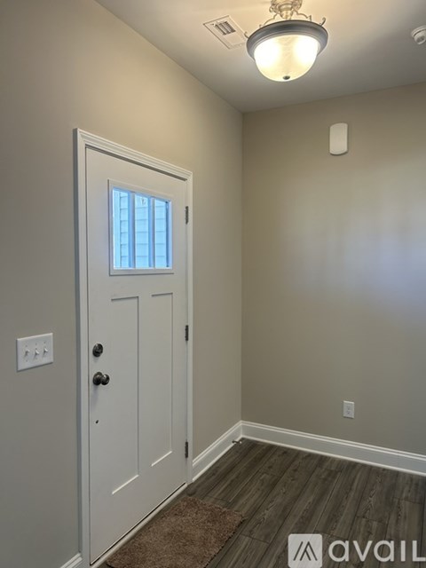 A white door with a window in the middle is in a room with a brown rug on the floor.