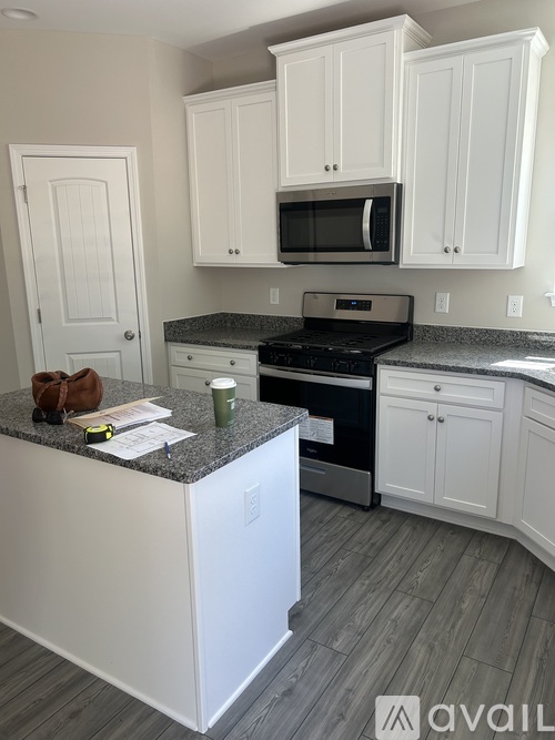 A kitchen with white cabinets and a granite countertop.