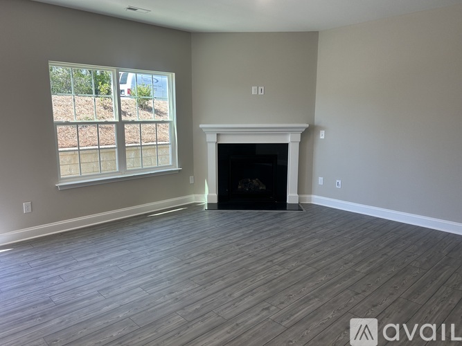 A room with a fireplace and a window overlooking a fenced area.