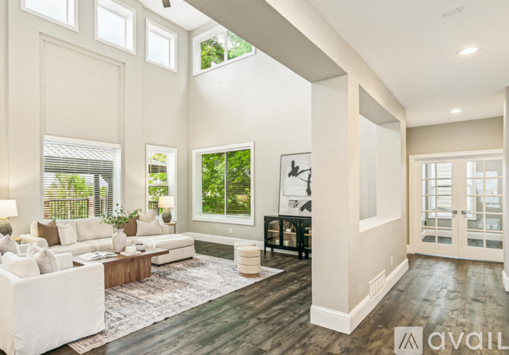 A spacious living room with a white sofa and a rug.