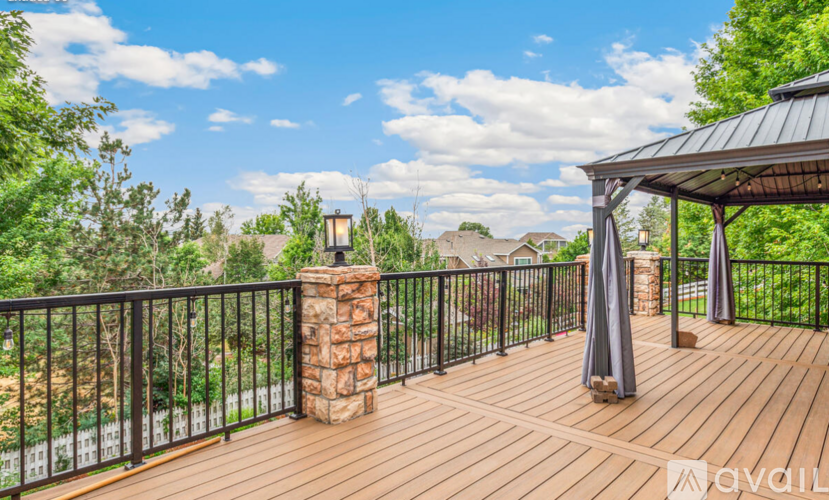 A wooden deck with a gazebo and a stone pillar.