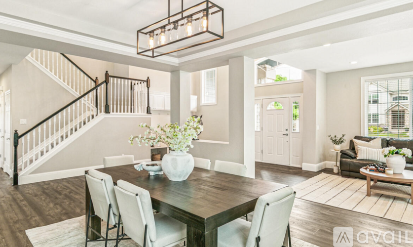 A modern dining room with a wooden table and white chairs.