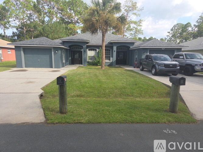 A house with a palm tree in front and two cars parked in the driveway.