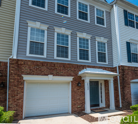 A two-story house with a white garage door and brick wall.