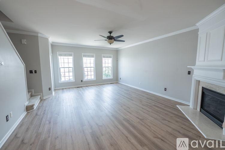 A spacious living room with a fireplace and a ceiling fan.