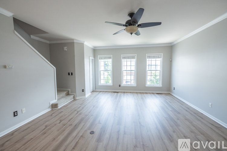 A spacious room with a ceiling fan and wooden flooring.