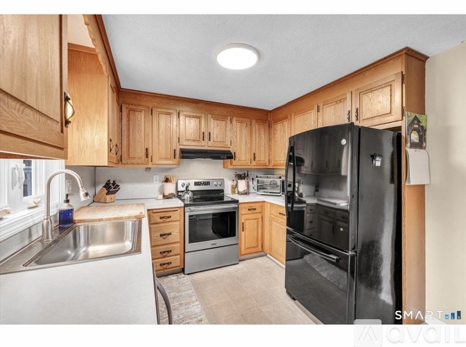 A kitchen with wooden cabinets and a black refrigerator.