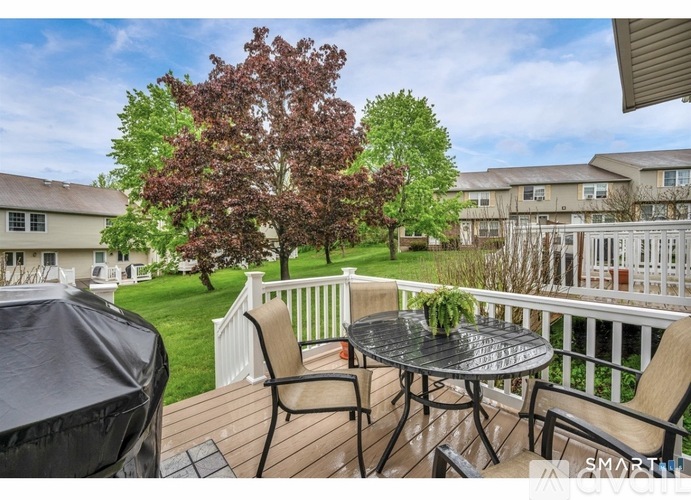 A patio with a table and chairs overlooking a grassy area.