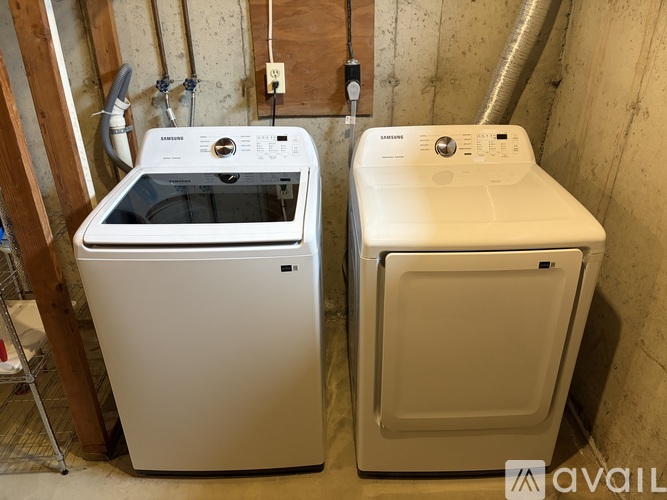 Two white front loading washing machines in a basement.