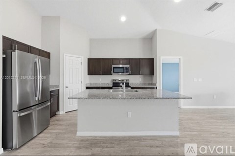A modern kitchen with a stainless steel refrigerator and a central island.