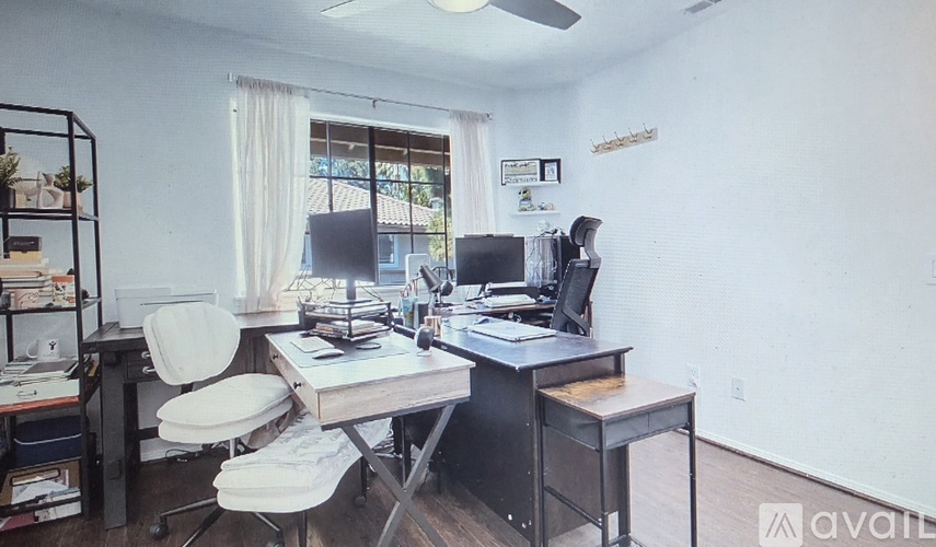 A room with two desks and chairs, one of which is empty.