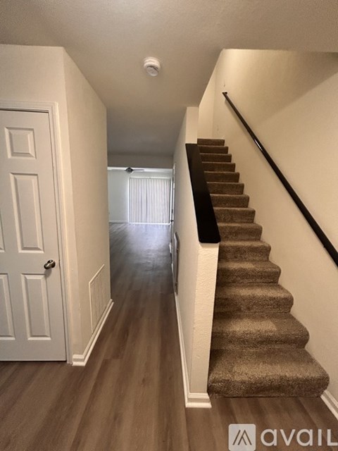 A hallway with a staircase and a white door.