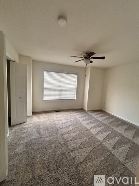 A room with a ceiling fan and a window with blinds.