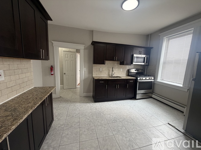 A kitchen with black cabinets and a white door.