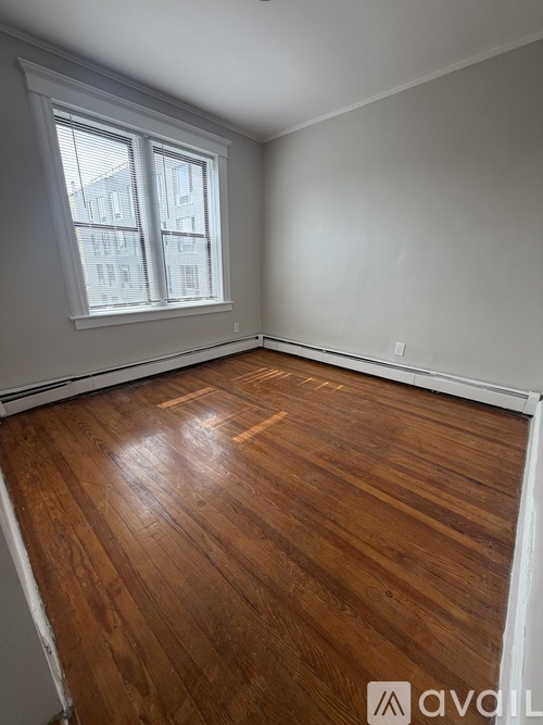 A room with wooden flooring and a window.