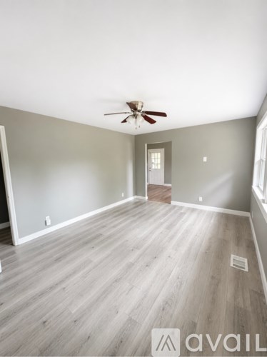 A room with a ceiling fan and wooden flooring.