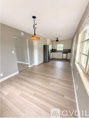 A well-lit kitchen with wooden flooring and a hanging light fixture.