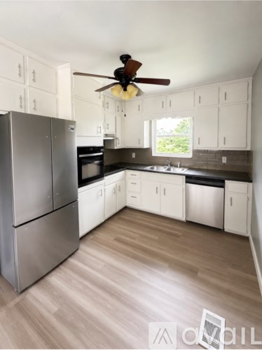 A modern kitchen with a stainless steel refrigerator and wooden flooring.