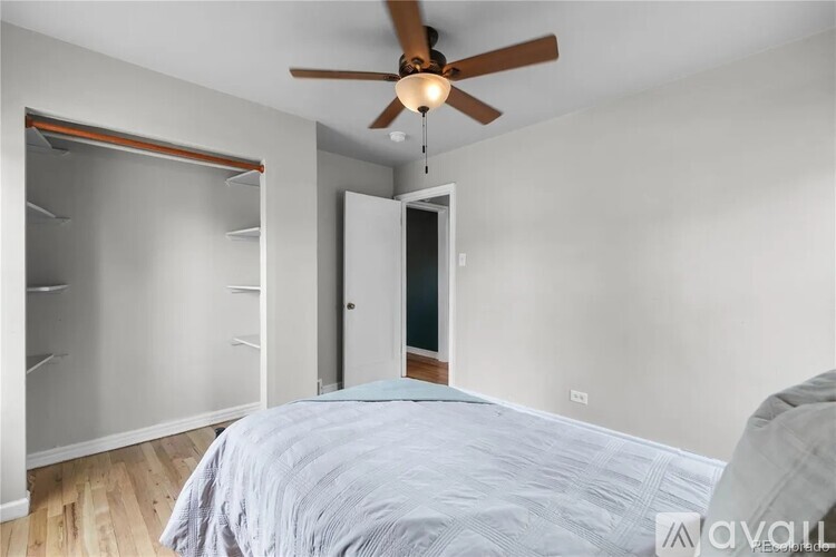 A bedroom with a bed, a ceiling fan, and a closet.
