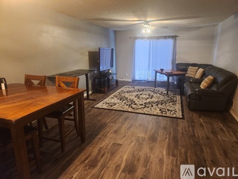 A living room with a wooden floor and a rug in the center.
