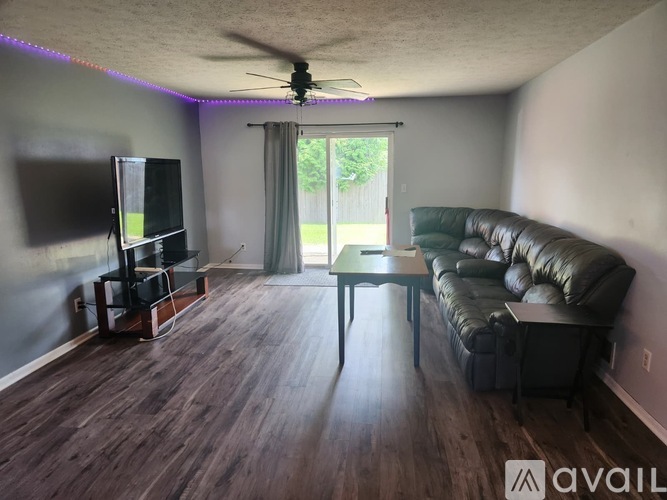 A living room with a black leather couch and a television.