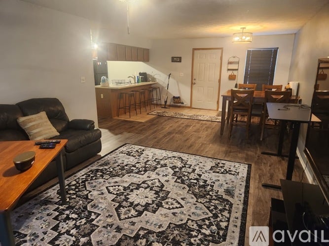 A living room with a black couch and a rug with a wooden table in front of it.