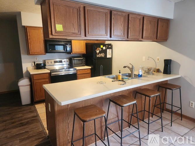 A kitchen with a white counter and brown stools.