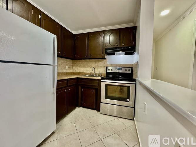 A kitchen with a white refrigerator, stainless steel oven, and brown cabinets.